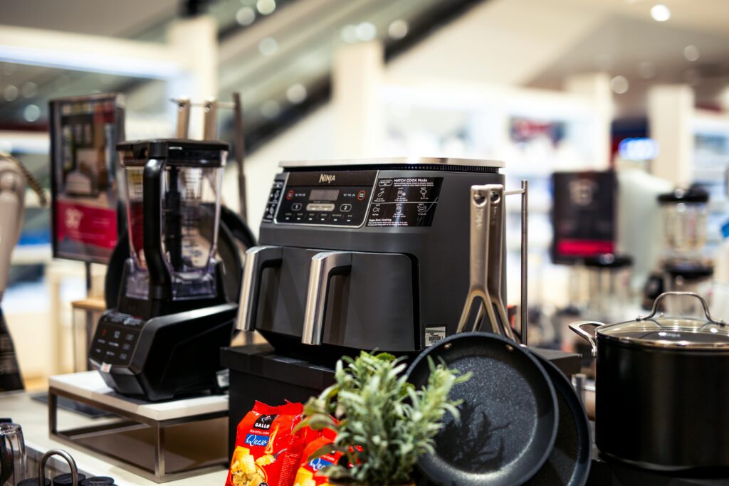 Showcase of modern kitchen appliances in a retail store, featuring blenders and cooking equipment.